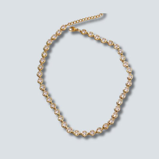 Gold necklace with clear stones on a light gray background